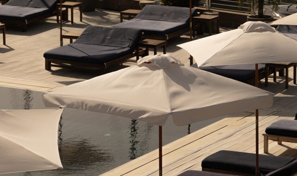 Personale del resort che prepara con cura i lettini a bordo piscina con teli rigati blu e bianchi.